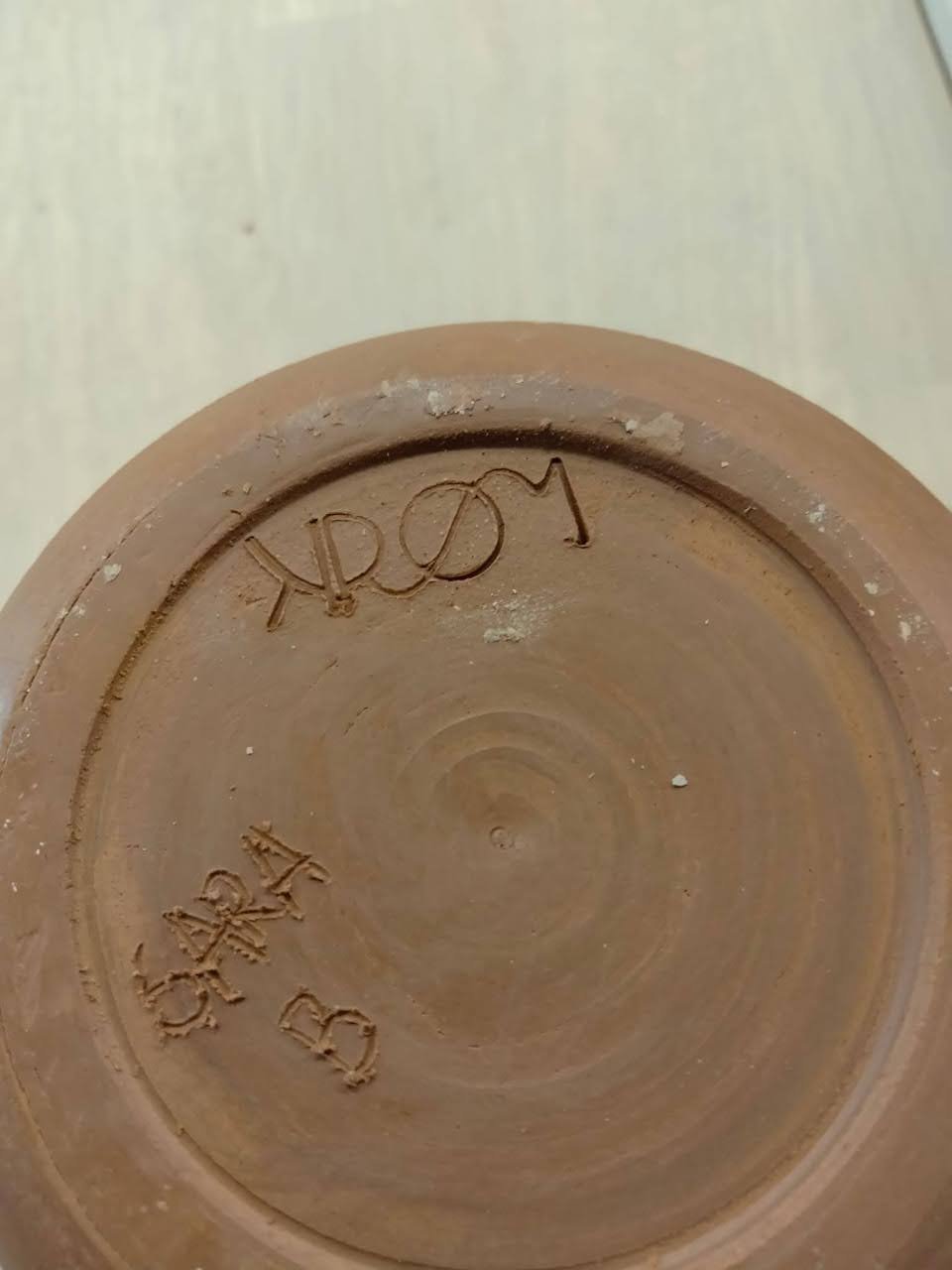 de bodem van een biscuit in rode klei met het logo van Atelier KROM Sara Dejonghe